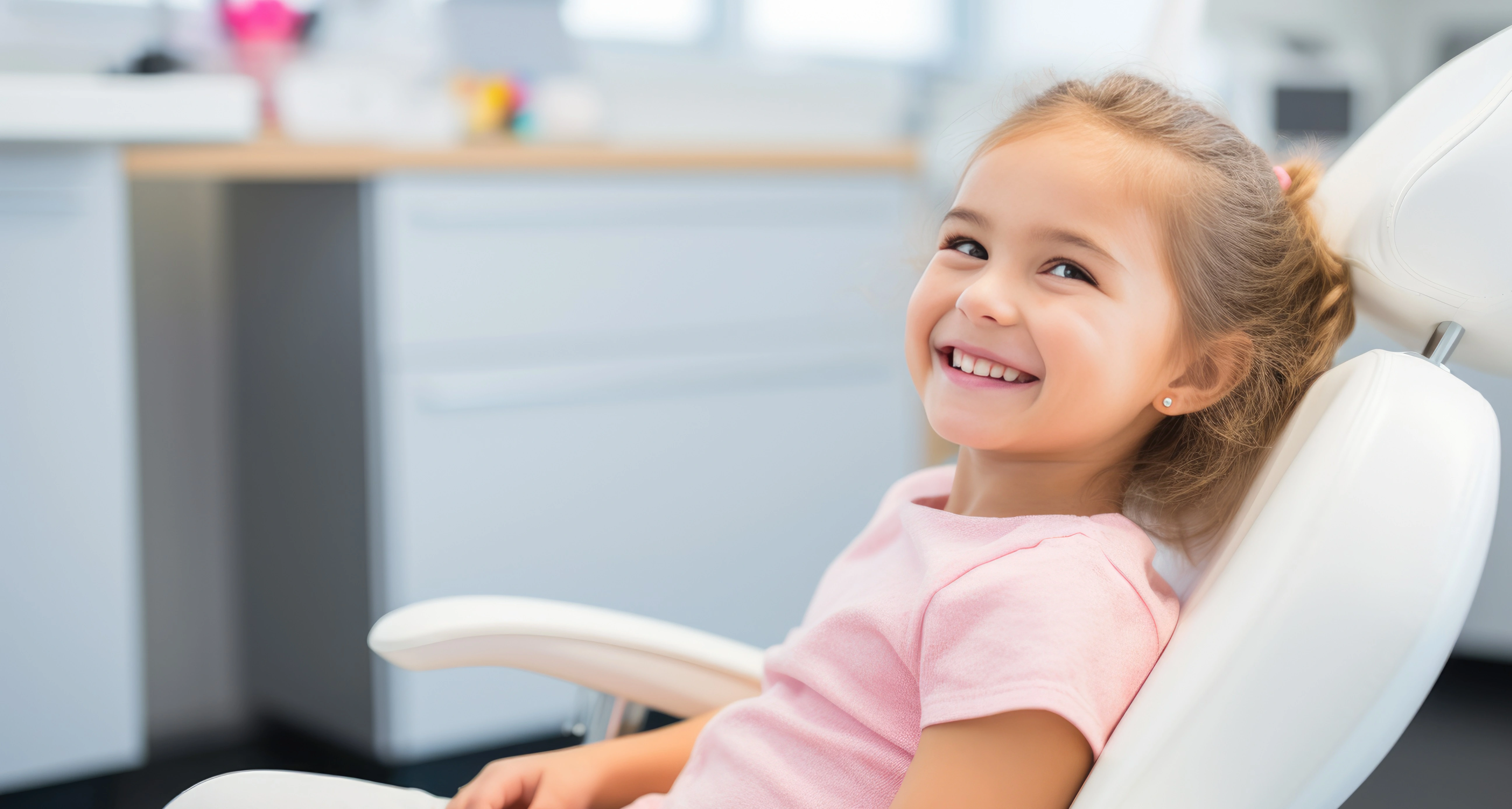 Kinder Zahni. Ein lächelndes Mädchen sitzt auf dem Behandlungsstuhl